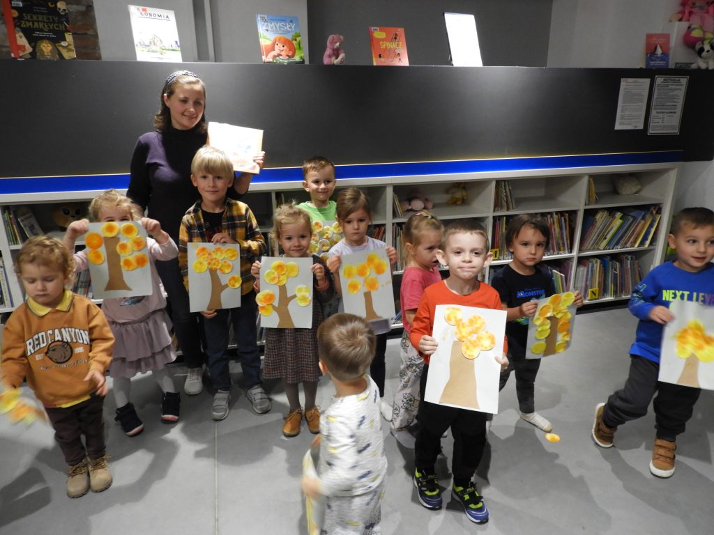 Zdjęcie grupowe, bibliotekarka trzyma książkę, dzieci prezentują zrobione prace plastyczne